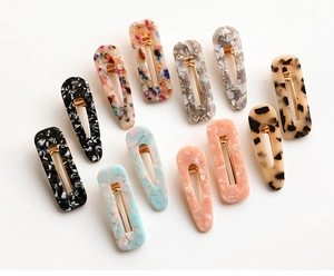 Flat lay of 12 acetate hair clips featuring leopard print and marble textures on metal base