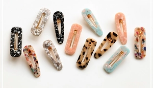 Flat lay of diverse acetate hair clips with marble patterns and gold metal spring bases