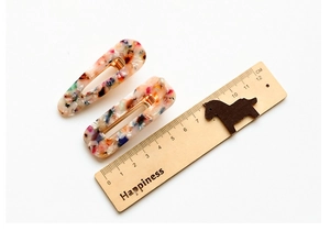 Detail view of leopard print acetate hair clips with dimensions shown on a wooden ruler
