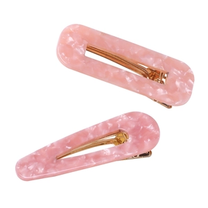 Detailed macro view of pink marble acetate hair clips with elegant gold-plated metal finish