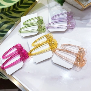 Cinq paires de barrettes à cheveux en résine colorée sur cartes blanches sur fond marbre