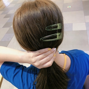Gros plan de deux pinces à cheveux vertes transparentes sur des cheveux bruns