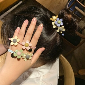 Close-up of macaron color flower hair ties set on a model's wrist and hair