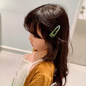 Gros plan d'un enfant portant une pince à cheveux en résine vert bonbon à texture gelée