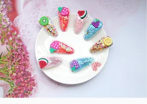 Barrettes à cheveux en forme de fruits avec paillettes colorées dans un plat blanc