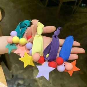 Detailed view of five colorful star pendant hair ties held in hand with ribbed texture elastic