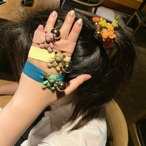 Detailed view of colorful knitted bear elastic hair ties worn on hand and in hair
