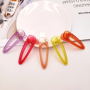 Lot de 5 pinces à cheveux transparentes colorées disposées sur une assiette en céramique