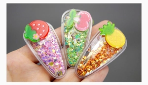 Detail of three colorful sequin hair clips featuring strawberry, cherry and pineapple shapes