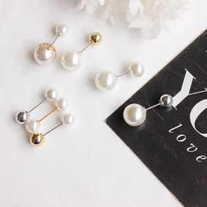 Detail view of pearl stud earrings with gold crowns on white fabric background