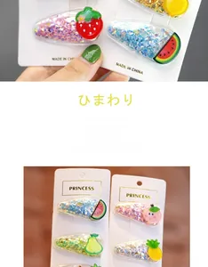 Detail of colorful sequin hair clips with assorted resin fruit charms on a white display card