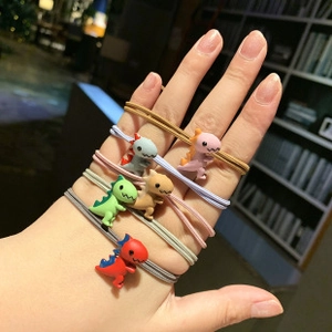 Close-up of colorful elastic hair ties with cute resin dinosaur charms in hand