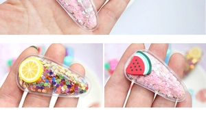 Détail de barrettes transparentes avec paillettes colorées et breloques fruits pour filles