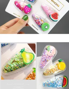 Macro detail of kids fruit hair clips featuring colorful sequins and acrylic strawberry shapes