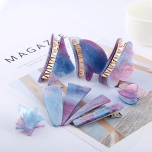 Detailed arrangement of acetate hair claws and clips with blue-purple marble texture on a desk
