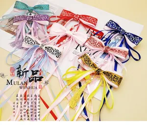 Detail of colorful Hanfu hair clips with silk ribbons and beaded tassels on a flat lay background