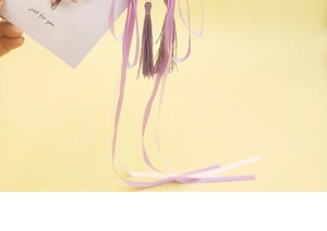 Detailed view of elegant purple silk ribbons with soft tassels and white pearl beads