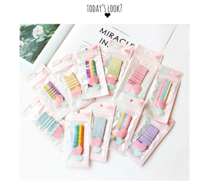 Close-up of colorful candy-colored bobby pins in heart-decorated packaging on a white desk