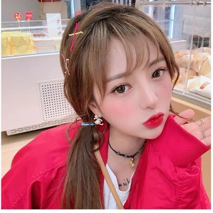 Detail view of colorful wavy hair clips and pearl letter earrings on a model in a bakery