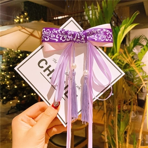 Detail of pink and purple silk bow hair clip with floral patterns and pearl tassels