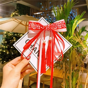Detail of red Hanfu bow hair clip with white pearls and long silk tassels