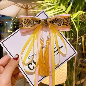 Detailed view of handmade bow hair clip with vintage patterns and elegant long tassels
