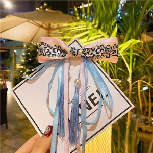 Detail of pink and blue silk bow hair clip with tassel ribbons and white imitation pearls