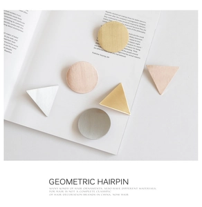 Detailed macro view of geometric hair clips showing brushed metal texture and finishes