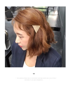 Macro shot of a geometric gold brushed triangle hair clip worn on a female model