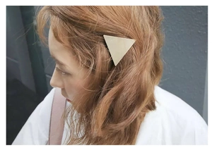 Polished golden triangular hair clip detail shown on wavy hair for a stylish look