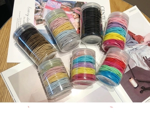 Close-up of colorful elastic hair ties set in a transparent cylinder storage jar