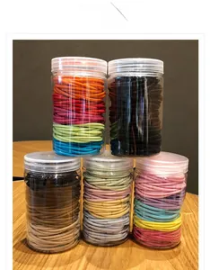 Set of colorful elastic hair ties in transparent jars shown on a wooden table