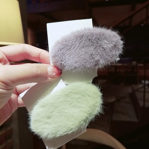 Detail of plush faux fur hair clips in purple and green showing soft fuzzy texture