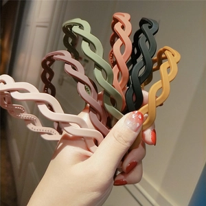 Detail showing wavy matte plastic headbands in various candy colors held in hand