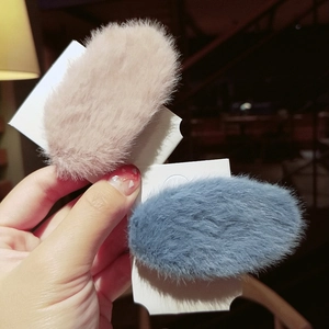 Close-up of plush oval hair clips in pink and blue on display cards