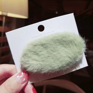 Detailed macro view of a soft light green plush rabbit fur hair clip on a display card
