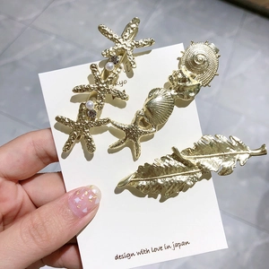 Lot de barrettes dorées avec étoile de mer, coquillage et perles sur support