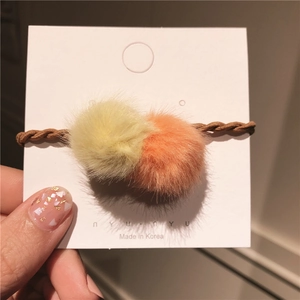 Detailansicht der flauschigen Kunstfell-Pompons an einem braunen Spiral-Haargummi
