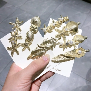 Détails de barrettes dorées avec étoile de mer, coquillage, perles et strass brillants