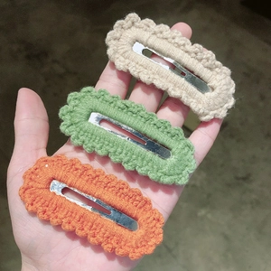 Macro detail of three handmade crochet wave pattern snap hair clips in vibrant colors