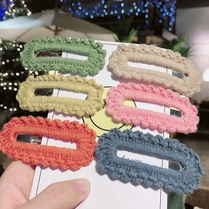 Close-up of six colorful crochet knit hair clips with scalloped edges on display card