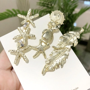 Détail d'un lot de 3 barrettes en métal doré avec motifs étoile de mer, coquillage et perles