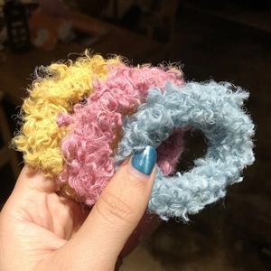 Close-up of fuzzy lamb wool hair ties in yellow, pink and blue colors with curly texture