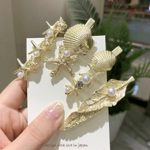 Barrettes dorées en étoile de mer, coquillage et plumes avec perles sur carte