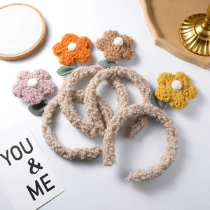Macro detail of four plush flower headbands in pink, orange, brown and yellow colors