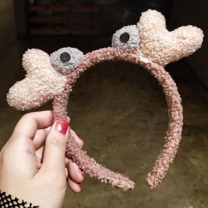 Détail d'un serre-tête en peluche rose avec texture laine d'agneau et yeux de dessin animé