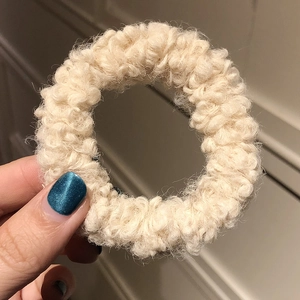 Close-up of soft cream lamb wool scrunchie texture with fuzzy plush fibers