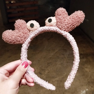 Détail d'un bandeau en peluche rose avec des yeux de dessin animé et des cœurs