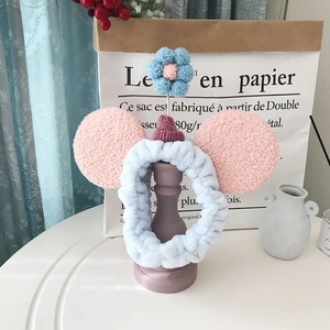 Detail van de blauwe pluche hoofdband met roze oren en gehaakte bloem voor huidverzorging