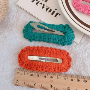 Handmade crochet knit hair clips in orange and green with wave edges on a white background